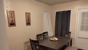 A dining room with a dark wooden table, four chairs, and a bench. There are two framed pictures on the wall. - Quiet & Downtown Smart TVs in all bedrooms, minutes from base. (Havelock)