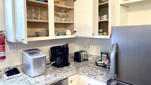 A kitchen with white cabinets, a stainless steel refrigerator, a toaster, a coffee maker, and a marble countertop. - Quiet & Downtown Smart TVs in all bedrooms, minutes from base. (Havelock)