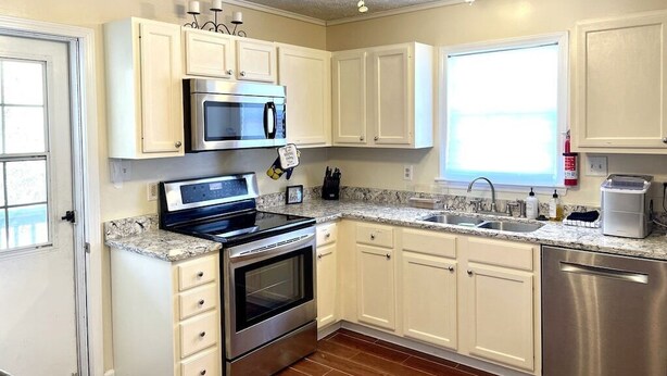 A kitchen with white cabinets, stainless steel appliances, a granite countertop, and a ceiling fan. - Quiet & Downtown Smart TVs in all bedrooms, minutes from base. (Havelock)