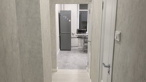 A hallway leading to a kitchen with a refrigerator and microwave. - Perfect location (Minsk)