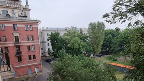 A residential area with a red building, a black car parked on the street, and a large tree in the foreground. - Perfect location (Minsk)