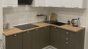 A modern kitchen with a black stove, white cabinets, and a wooden countertop. - Perfect location (Minsk)
