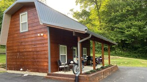 A wooden cabin with a covered porch, a motorcycle, and a barbecue grill. - Dragon's Nest Mountain View (Robbinsville)