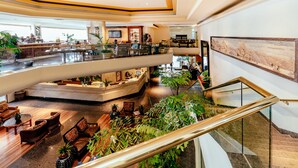 Un hall d’hôtel à plusieurs niveaux, doté d’un espace salon central, d’un bar et d’un escalier.
