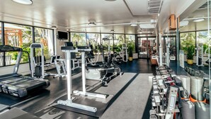 Une salle de sport moderne équipée de tapis de course, de vélos elliptiques et de poids libres.