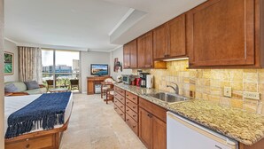 Une cuisine moderne avec des meubles en bois, des plans de travail en granit et une grande fenêtre donnant sur la ville.