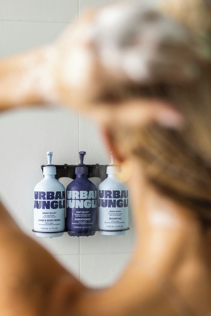 A bathroom with three bottles of Urban Jungle products: hand and body wash, conditioner, and shampoo.