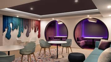 Un interior moderno con una mesa redonda, sillas, un sofá y una pared decorada con arte texturizado.