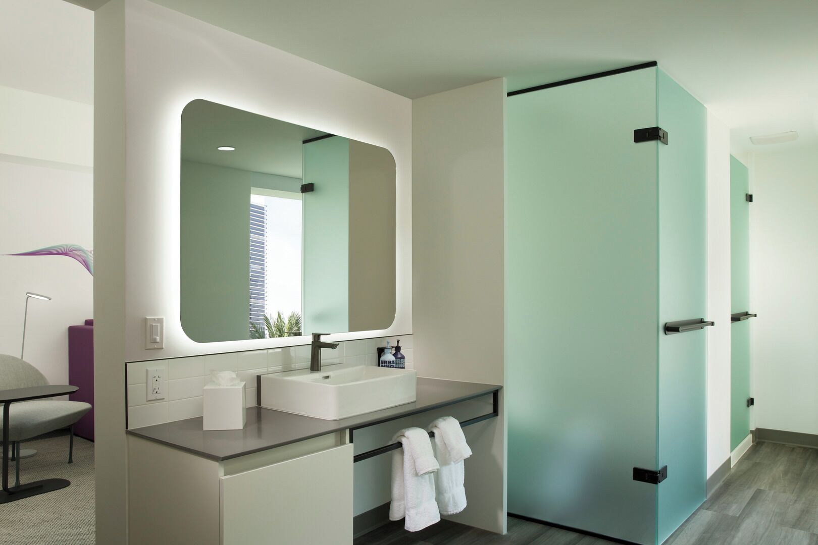 A modern bathroom with a large mirror, two sinks, and a glass door closet.