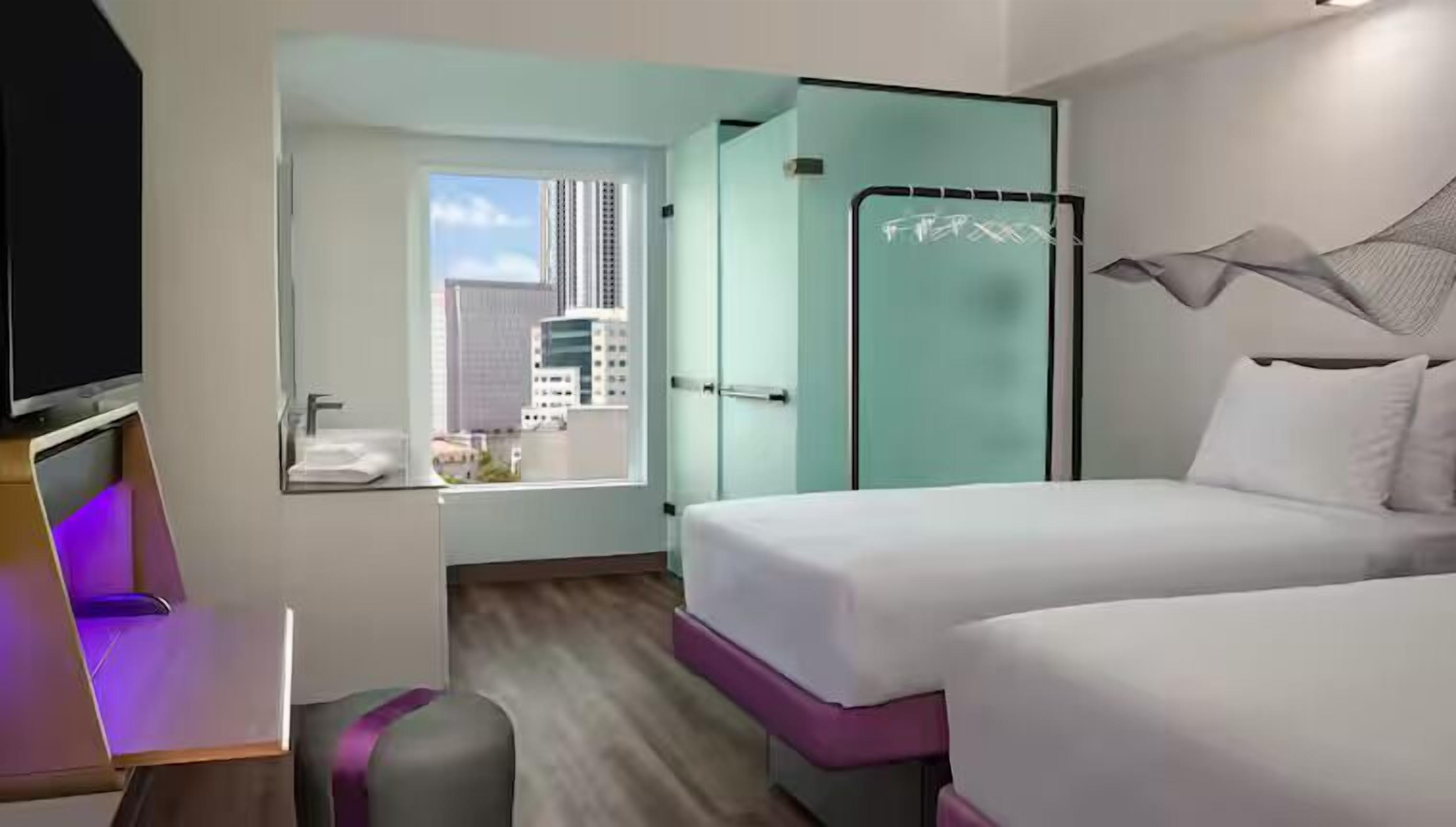 Une chambre d’hôtel comprenant un lit, un bureau, une chaise, une télévision, une fenêtre et une salle de bain.