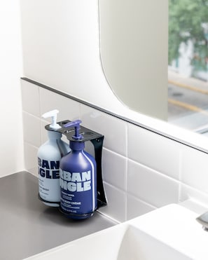 Two bottles of hand soap and a hand sanitizer on a bathroom counter.