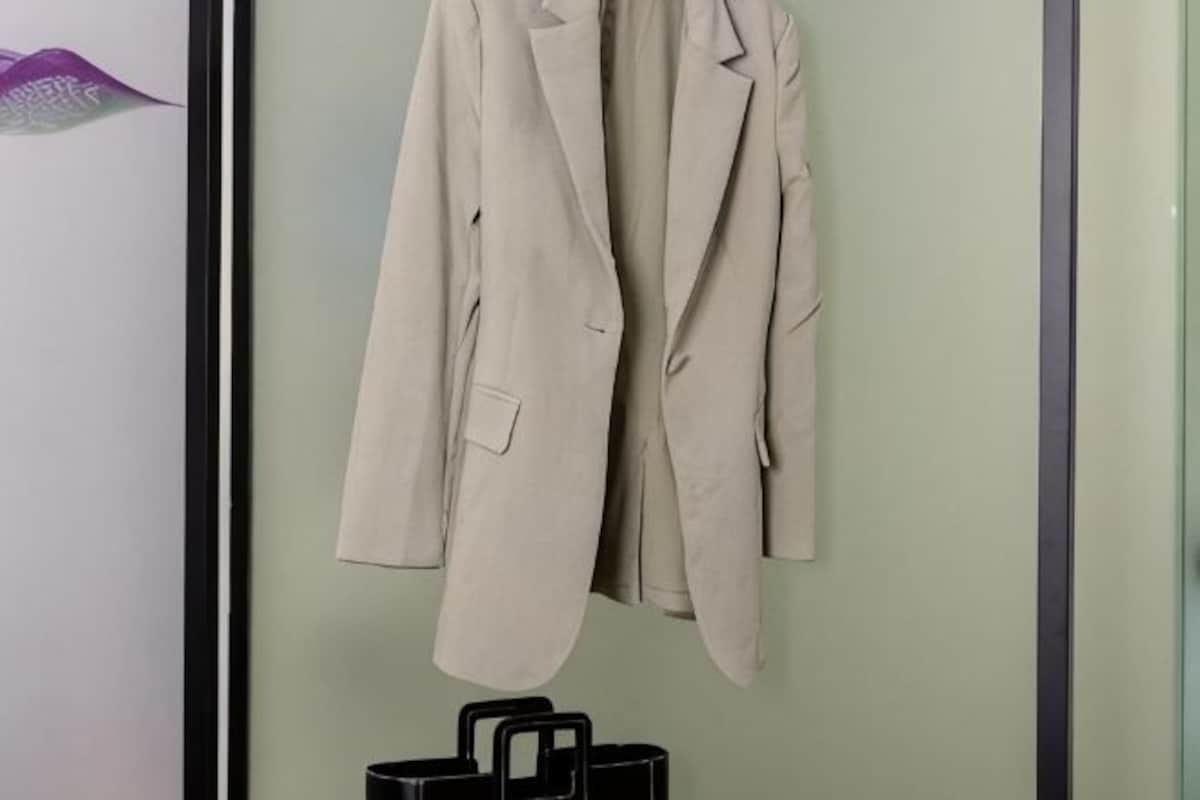 A beige suit jacket hanging on a wall.