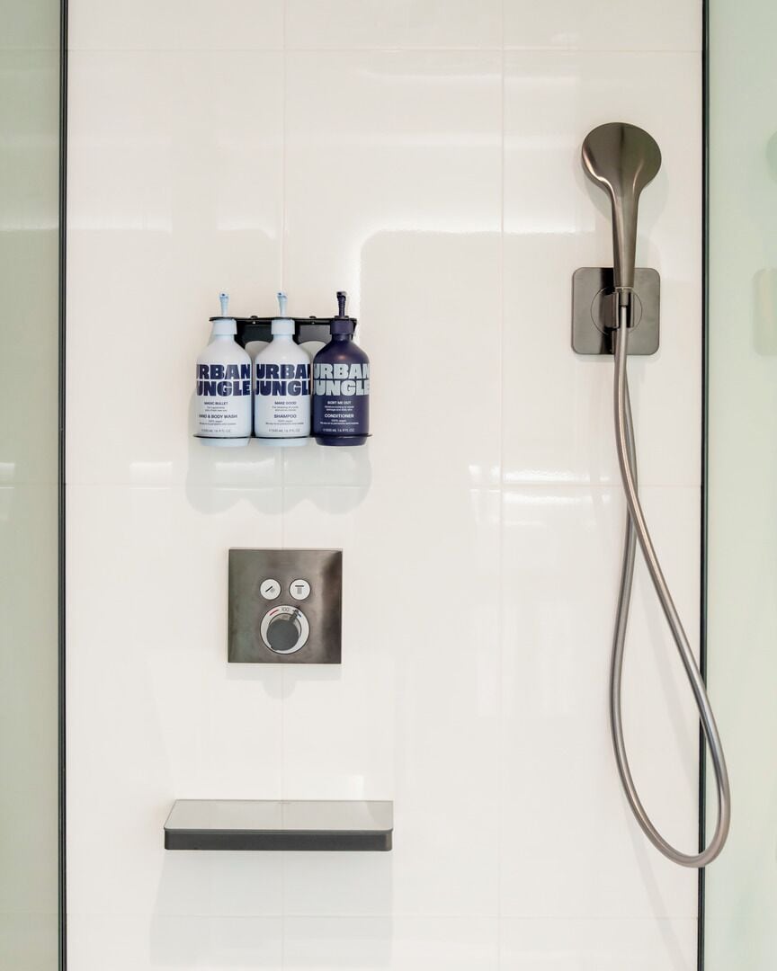 A bathroom with a shower, a soap dispenser, and a hand dryer.