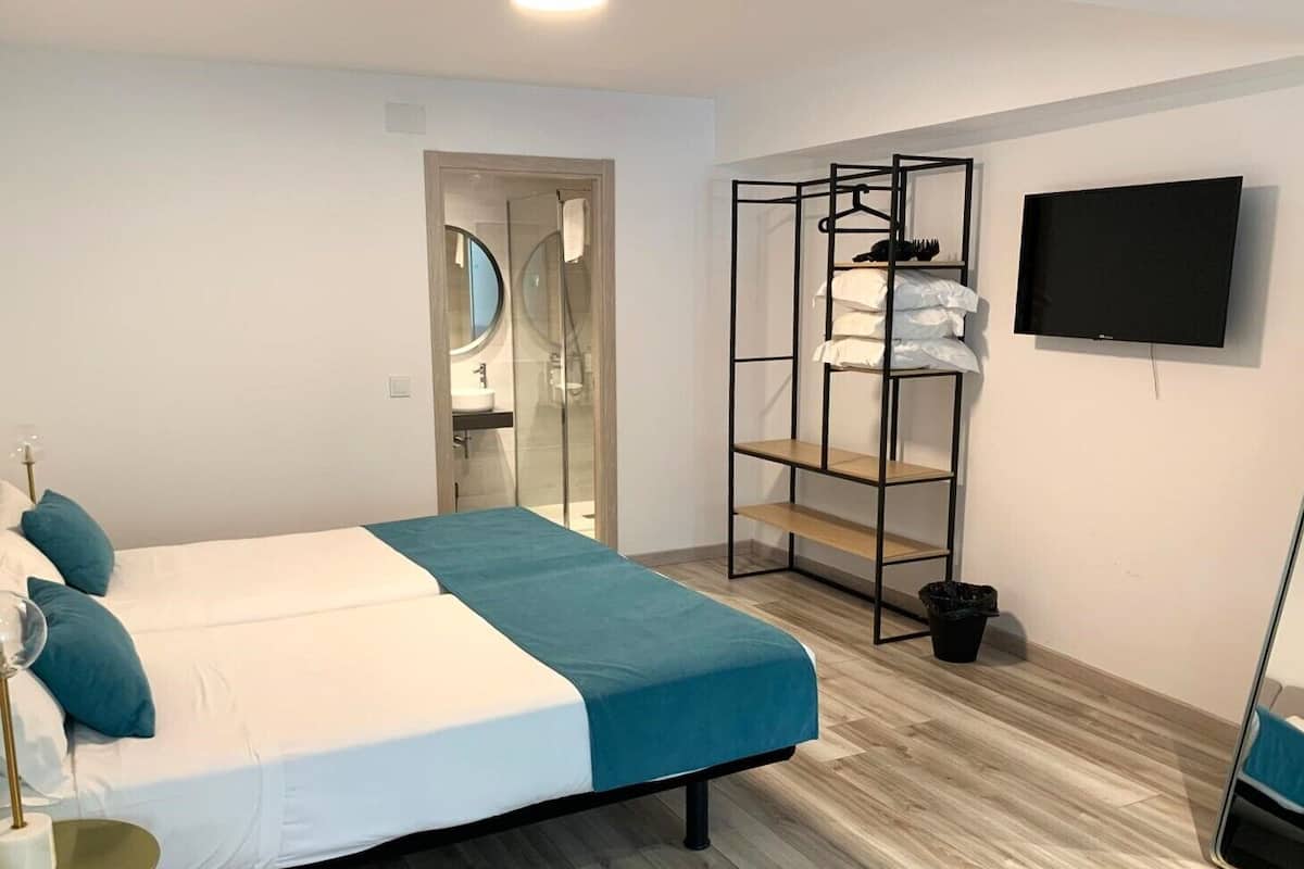 Ein modernes Hotelzimmer mit einem großen Bett, einem Einbauschrank, einem Fernseher und einem Badezimmer mit Glastür.