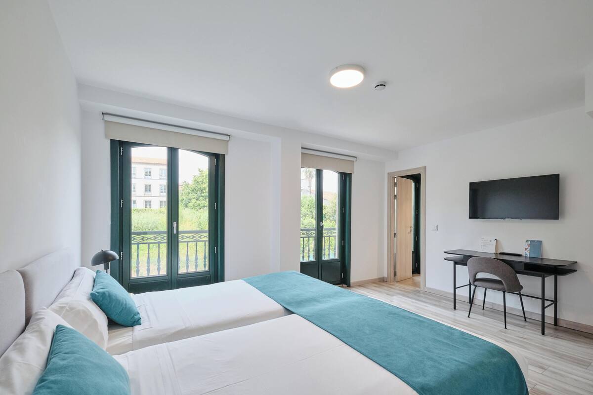Ein modernes Hotelzimmer mit einem großen Bett, einem Schreibtisch und einem Fernseher.