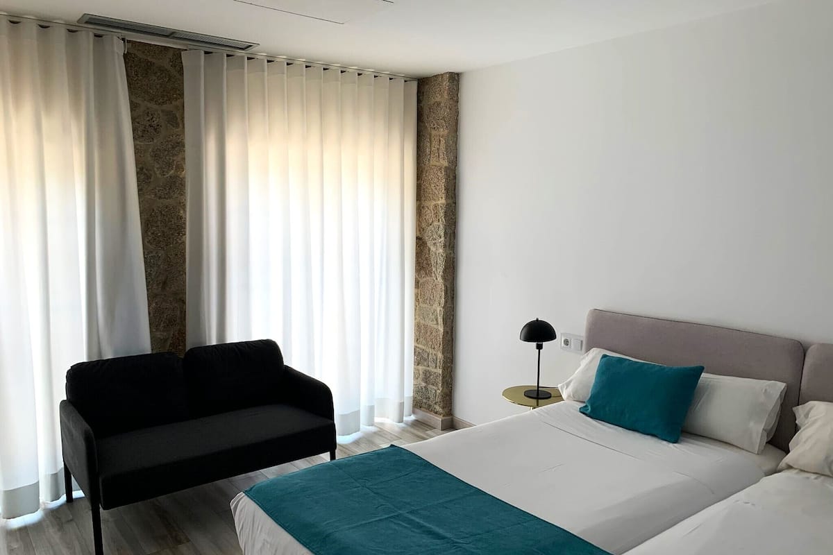 Ein Hotelzimmer mit Bett, Sitzbank, Nachttisch und Lampe.