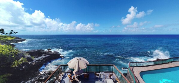 Una terraza con asientos al aire libre, piscina y vista al océano.
