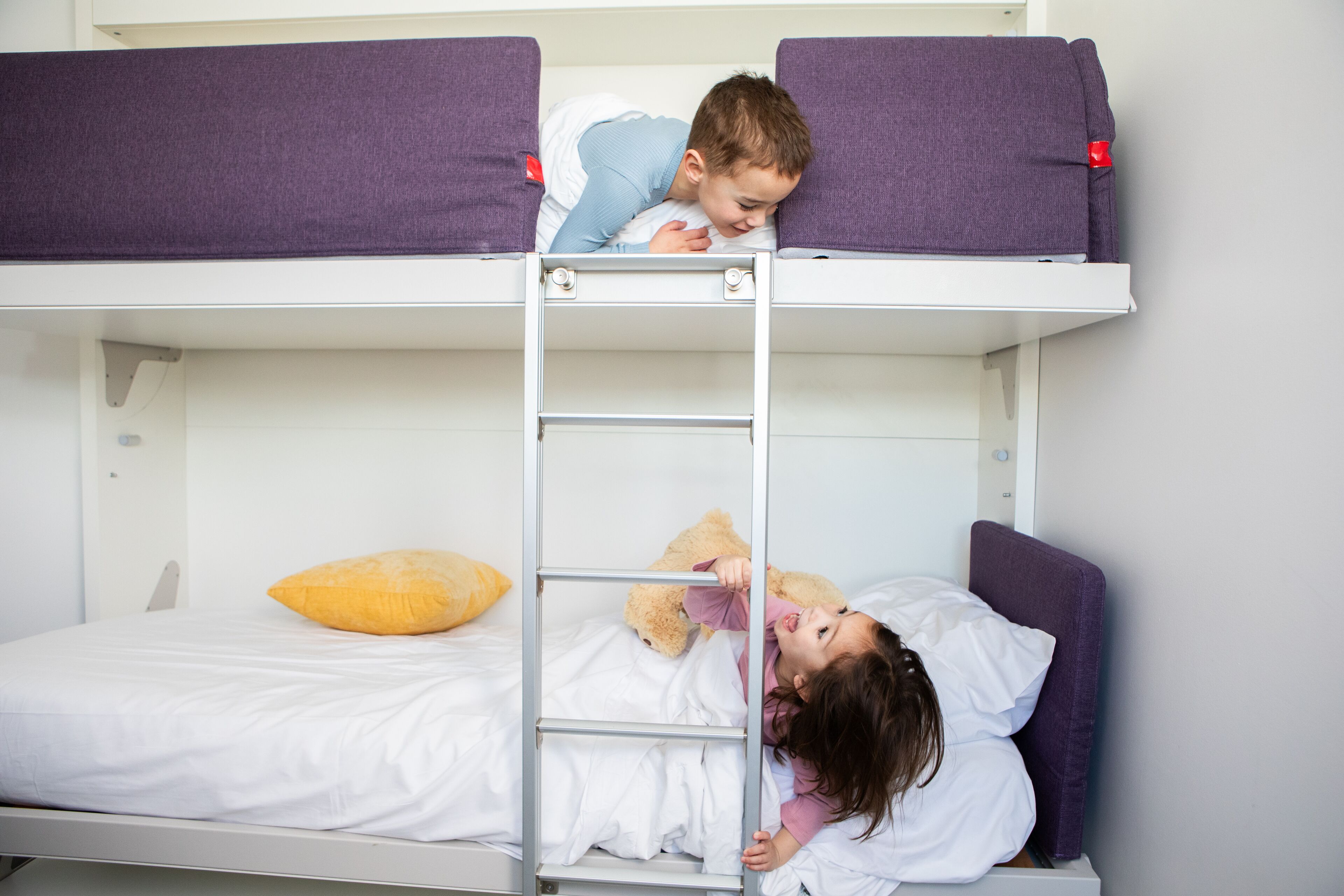 A bunk bed with two beds, a ladder, and pillows.