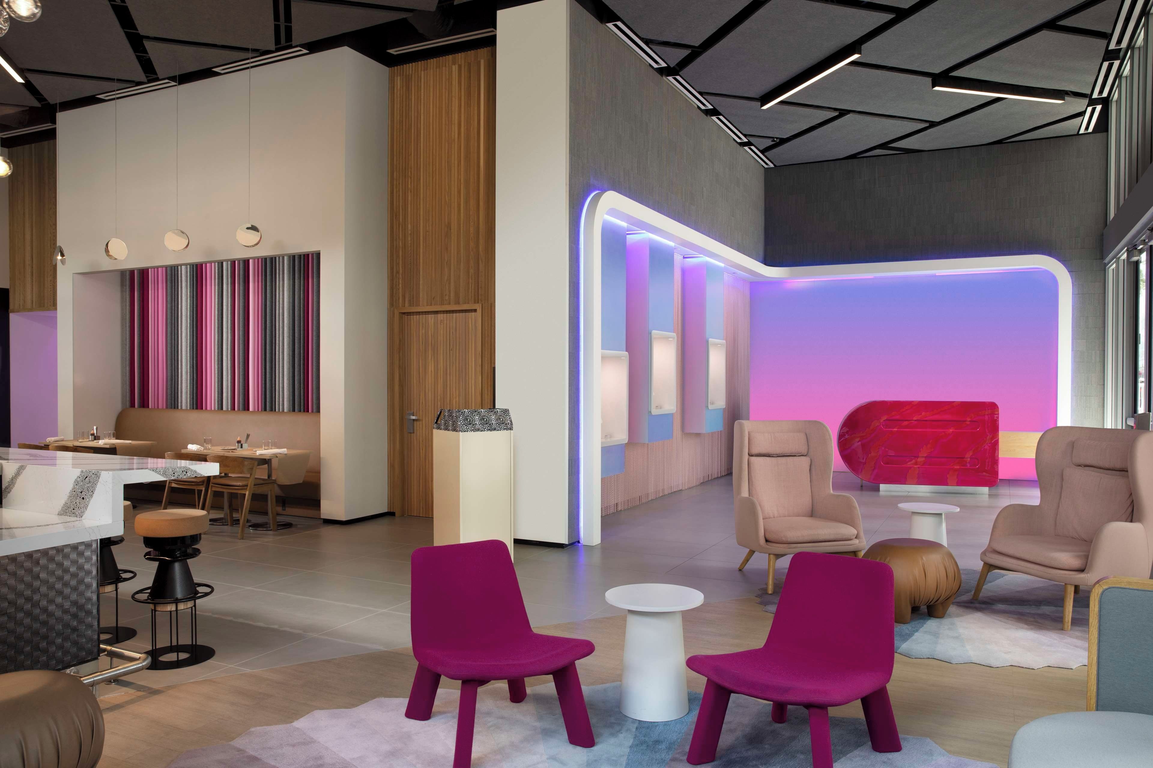 Un interior moderno con una zona de bar, asientos y una pared iluminada con neón llamativo.