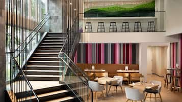 A modern interior with a staircase, seating area, and a green wall.