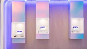 Three self-service kiosks with screens, mounted on a wall with a textured finish.
