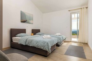 A bedroom with two beds, a painting, a balcony view, and a yoga mat. - Villa Solara (Sveti Lovreč Labinski)