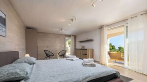 Ein modernes Schlafzimmer mit Bett, Schreibtisch und Blick ins Freie.