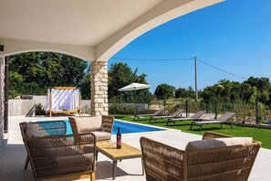 A covered outdoor area with wicker furniture, a pool, and lounge chairs. - Villa Solara (Sveti Lovreč Labinski)