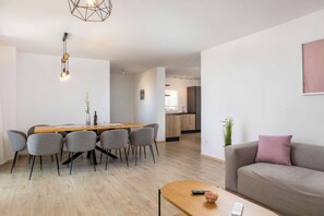 A modern living room with a sofa, a dining table with chairs, a coffee table, and a kitchen in the background. - Villa Solara (Sveti Lovreč Labinski)