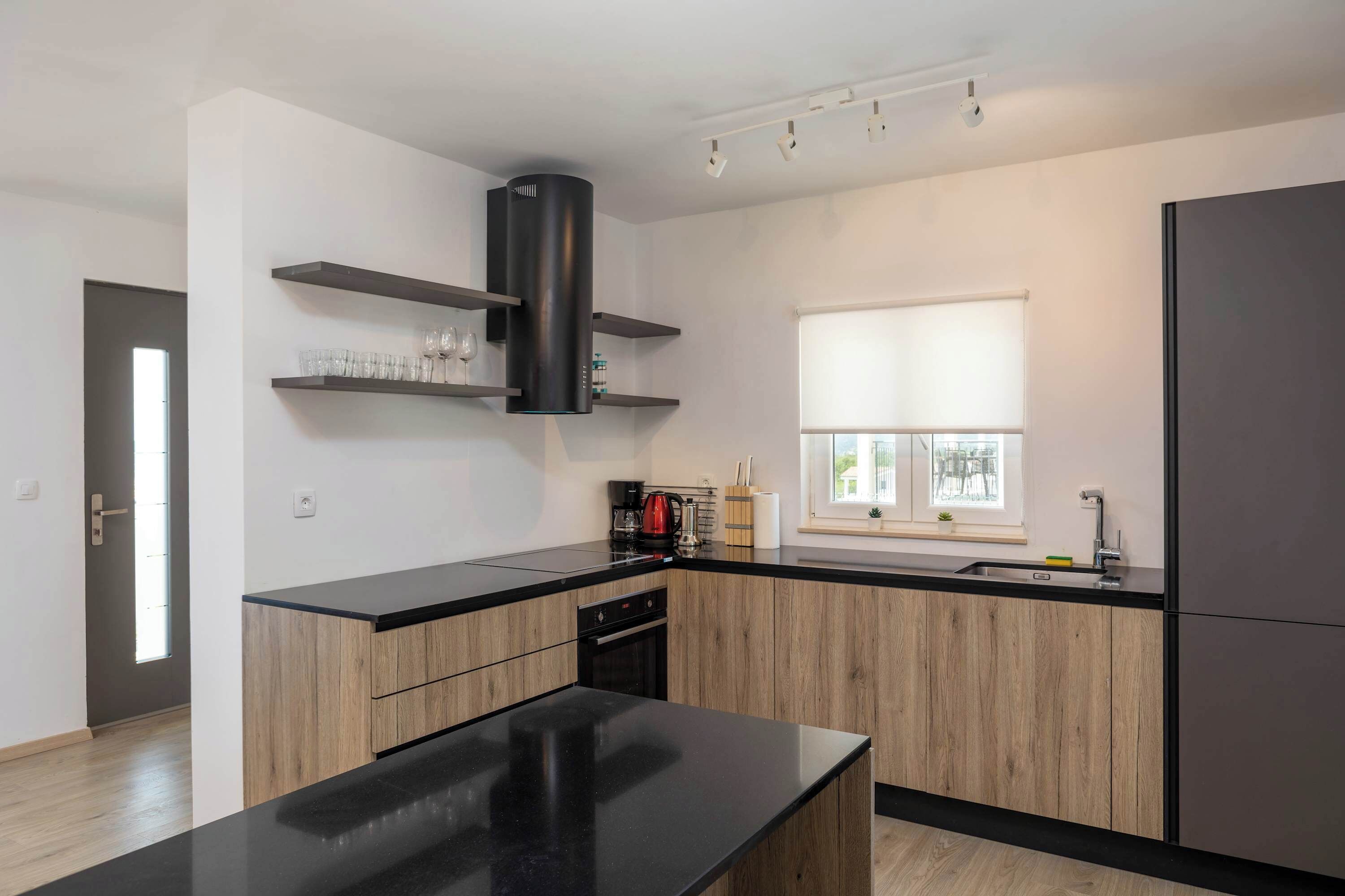 Una cucina moderna con mobili in legno, un piano di lavoro nero e un piano cottura integrato.