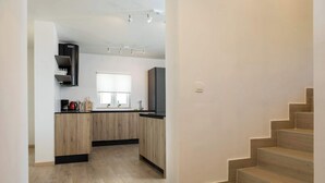 Eine moderne Küche mit Holzschränken, einer schwarzen Dunstabzugshaube und einem Fenster.