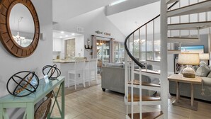 A spacious living area with a curved staircase, a kitchen with a view, and a large mirror on the wall. - Cottage 187, Spacious, Closest Cottages to the Beach, Free Beach Chair Service (Miramar Beach)