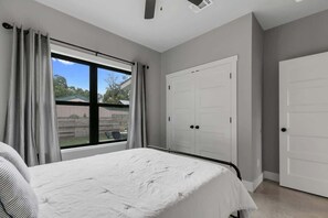 Une chambre à coucher avec un lit, une fenêtre avec des rideaux et une armoire blanche.