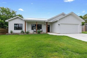A modern two-story house with a garage, a covered patio, and a well-maintained lawn.