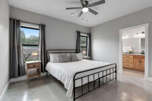 Une chambre à coucher avec un lit, des tables de chevet, un ventilateur de plafond et une vue par la fenêtre.