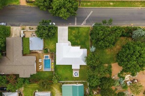 Vue aérienne d’une propriété résidentielle comprenant une grande maison, une piscine et une pelouse bien entretenue.