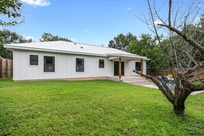 Une maison de plain-pied, à l’extérieur blanc et dotée d’un toit en métal à pente.