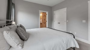 Een slaapkamer met een bed, een plafondventilator en een deur naar een badkamer.