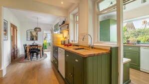 Une cuisine moderne avec un plancher en bois, des armoires vertes et un îlot central doté d’un évier.