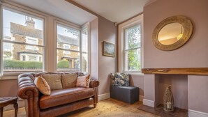 Un salon chaleureux avec un canapé en cuir marron, un banc gris et un grand miroir au mur.