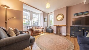 Un salon confortable avec une grande fenêtre, une cheminée et un téléviseur.