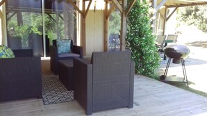 An outdoor patio with wicker furniture, a grill, and a view of greenery. - Garden apartment in the heart of nature 10 min from the beach and 5 min from the river (Conca)