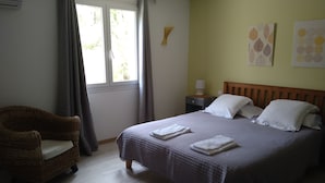 A neatly arranged bedroom with a bed, a chair, and a nightstand. - Garden apartment in the heart of nature 10 min from the beach and 5 min from the river (Conca)