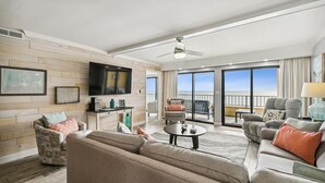 A spacious living room with a large flat-screen TV, comfortable seating, and a balcony with a view. - Surf Dweller 610 is a Stunning Gulf Front 2 BR - sleep 6 by RedAwning (Fort Walton Beach)