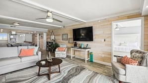 A modern living room with a sofa, armchair, coffee table, and a TV mounted on the wall. - Surf Dweller 610 is a Stunning Gulf Front 2 BR - sleep 6 by RedAwning (Fort Walton Beach)