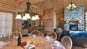 Ein Esszimmer mit Holzboden, einem Steinkamin, Holzsesseln und einem Kronleuchter.