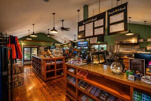 A cafe interior with wooden floors, hanging pendant lights, a menu board, and a cash register.