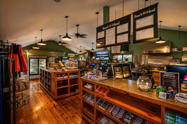 A cafe interior with wooden floors, hanging pendant lights, a menu board, and a cash register.