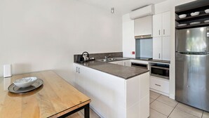 Eine moderne Küche mit weißen Schränken, einem Edelstahlkühlschrank, einer Mikrowelle und einem Holzespeisetisch mit einer Schüssel.