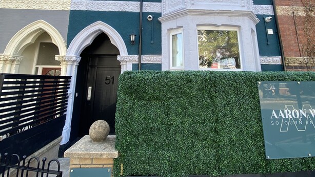 En bygning i viktoriansk stil med en mørkegrøn facade, hvide detaljer og et karnapvindue.